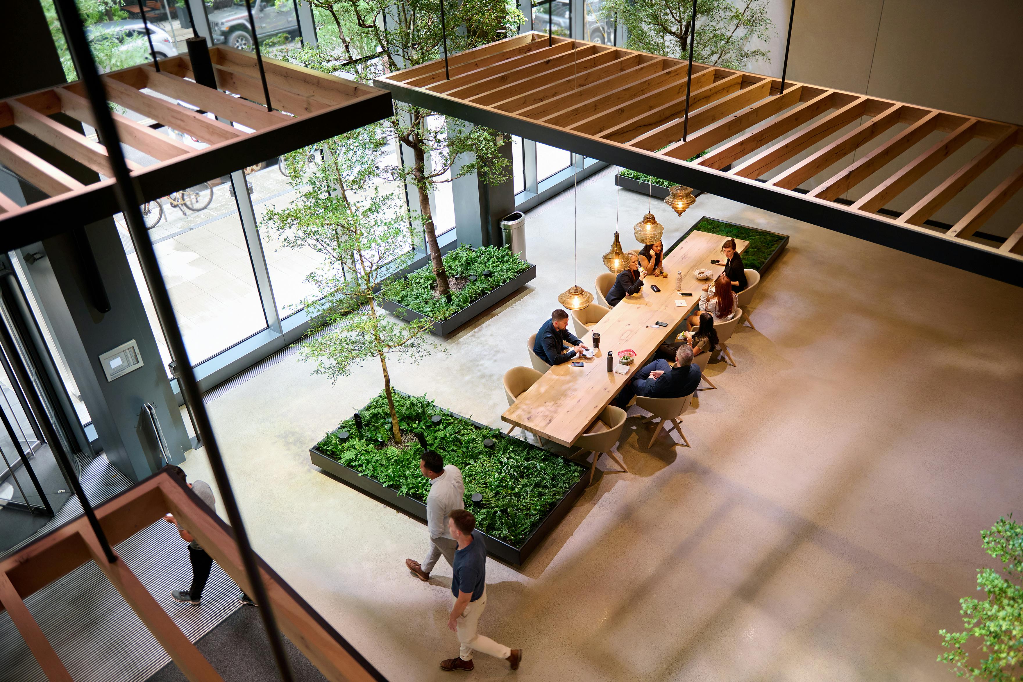 Two employees walking through an office lobby with greenery and warm light coming in through windows.