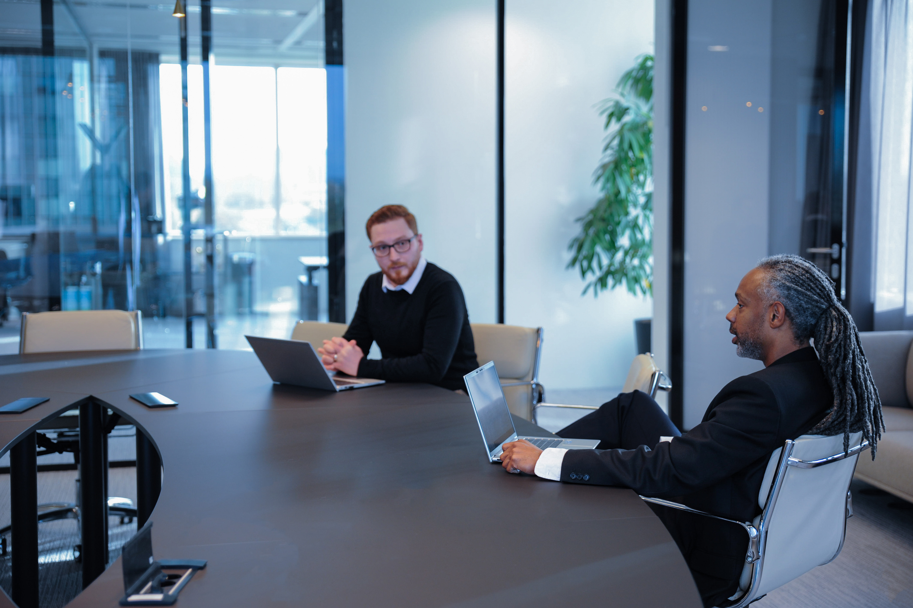 Two Fusion Worldwide employees working on their laptops in a conference room