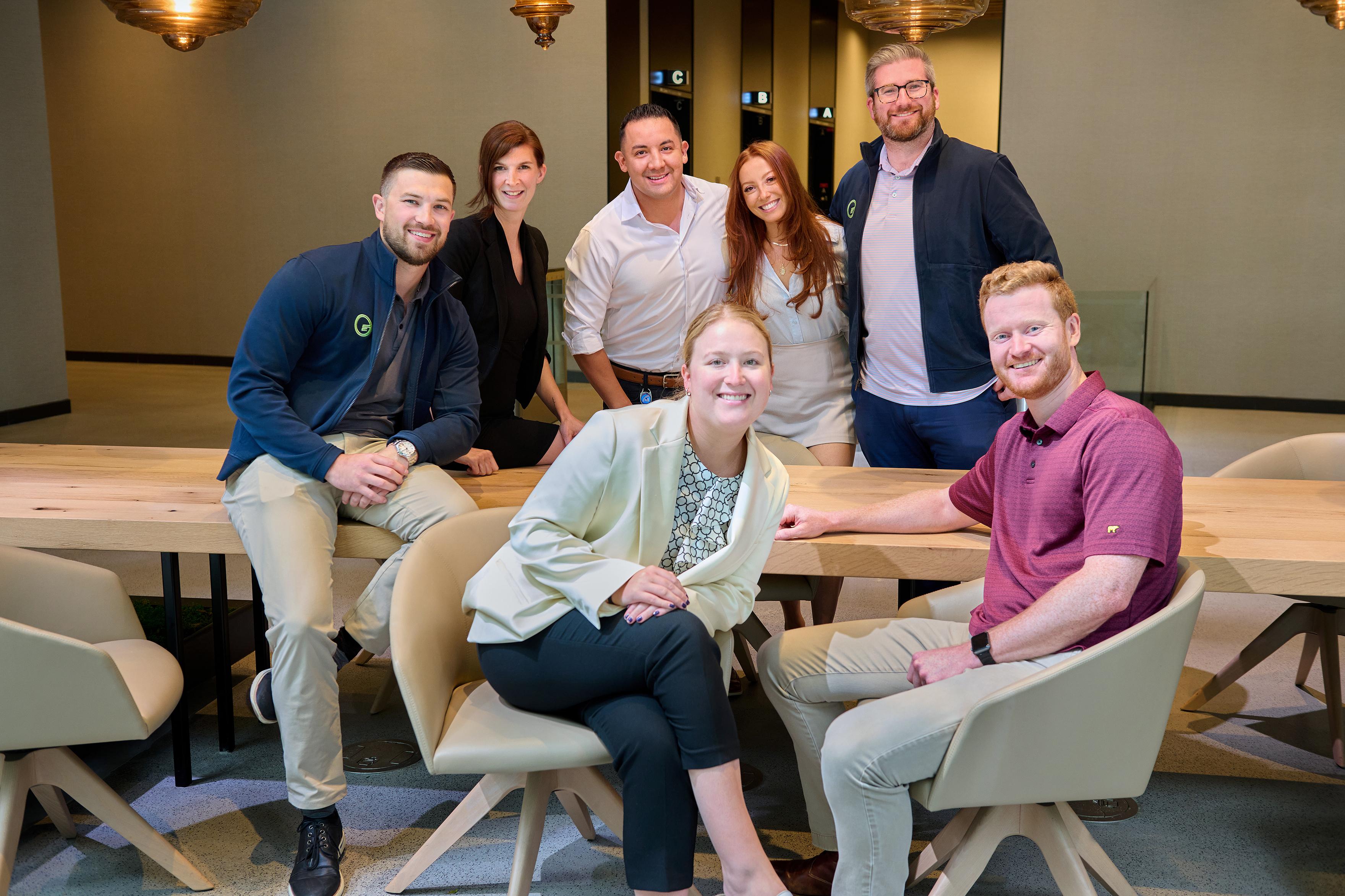 Five Fusion Worldwide employees sitting around a table for a meeting in a conference room